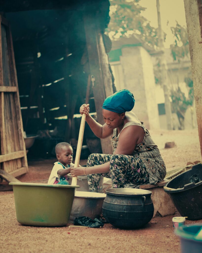 A woman and child in a traditional African kitchen cooking together.